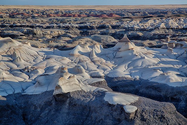 Grey and rust-colored hills in a treeless desert landscape in the Bisti De-Na-Zin Wilderness Area, New Mexico