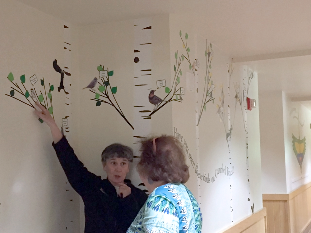 Staff pointing out birds put in trees to a visitor