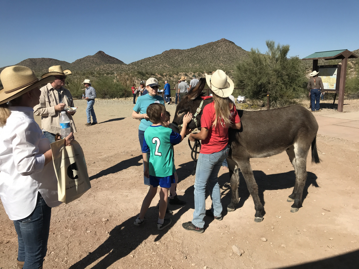 two children pet a brown burro