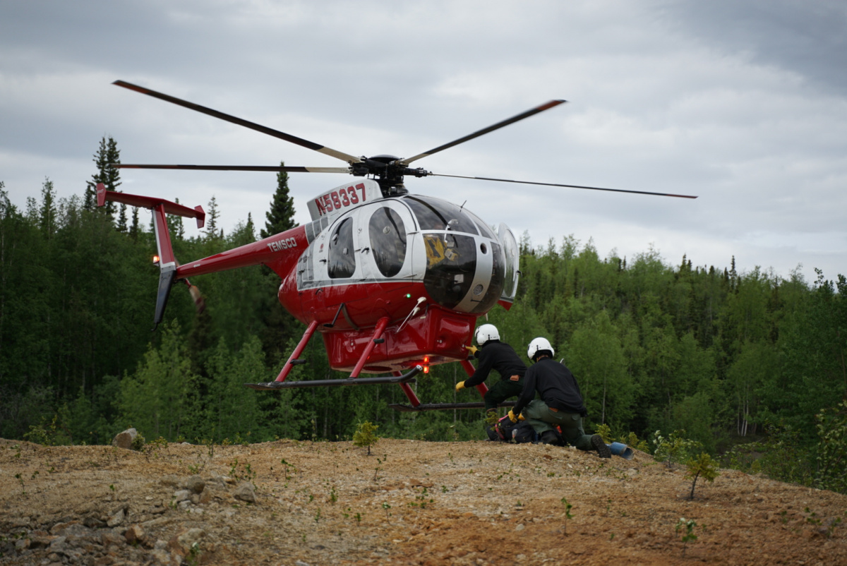 Two people under a hovering helicopter