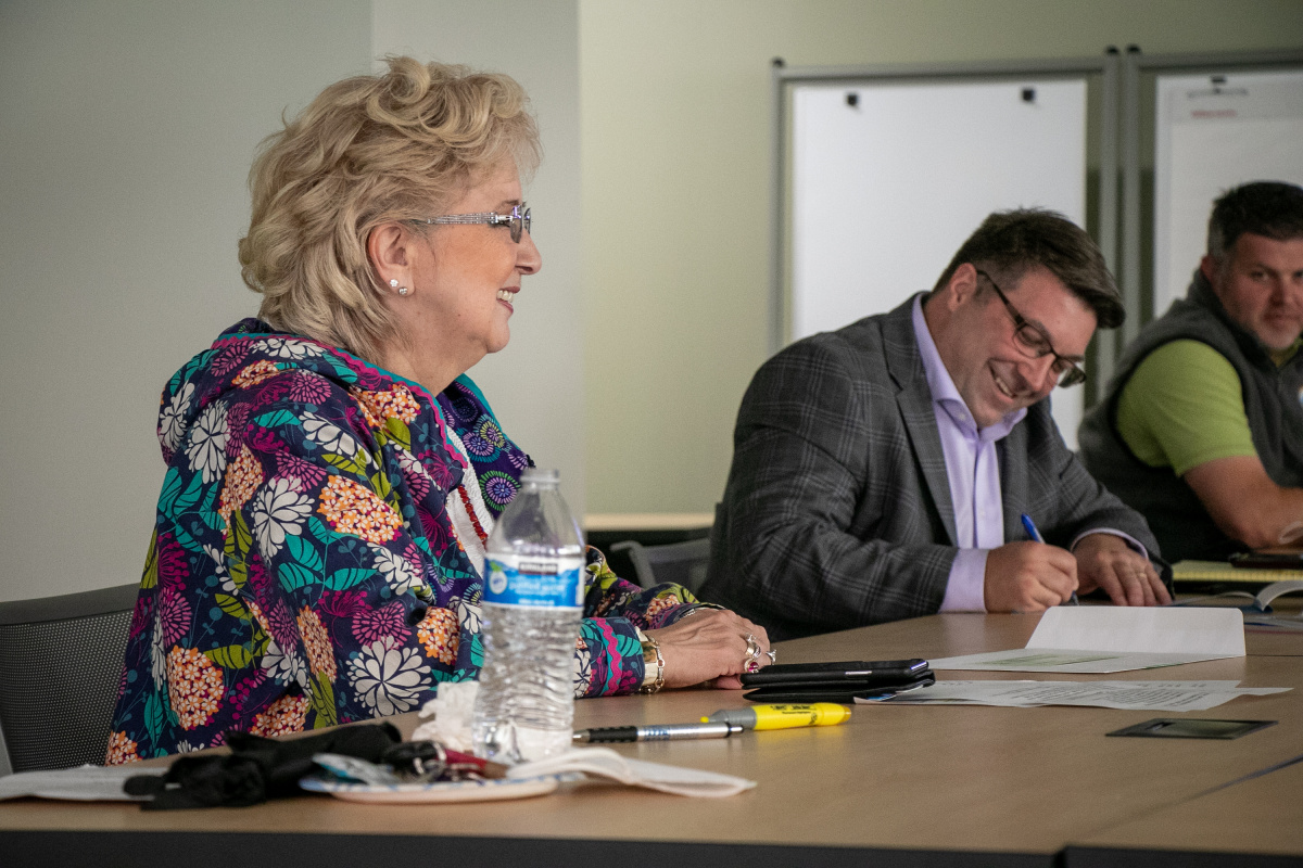 A man signs a paper while a woman watches and smiles