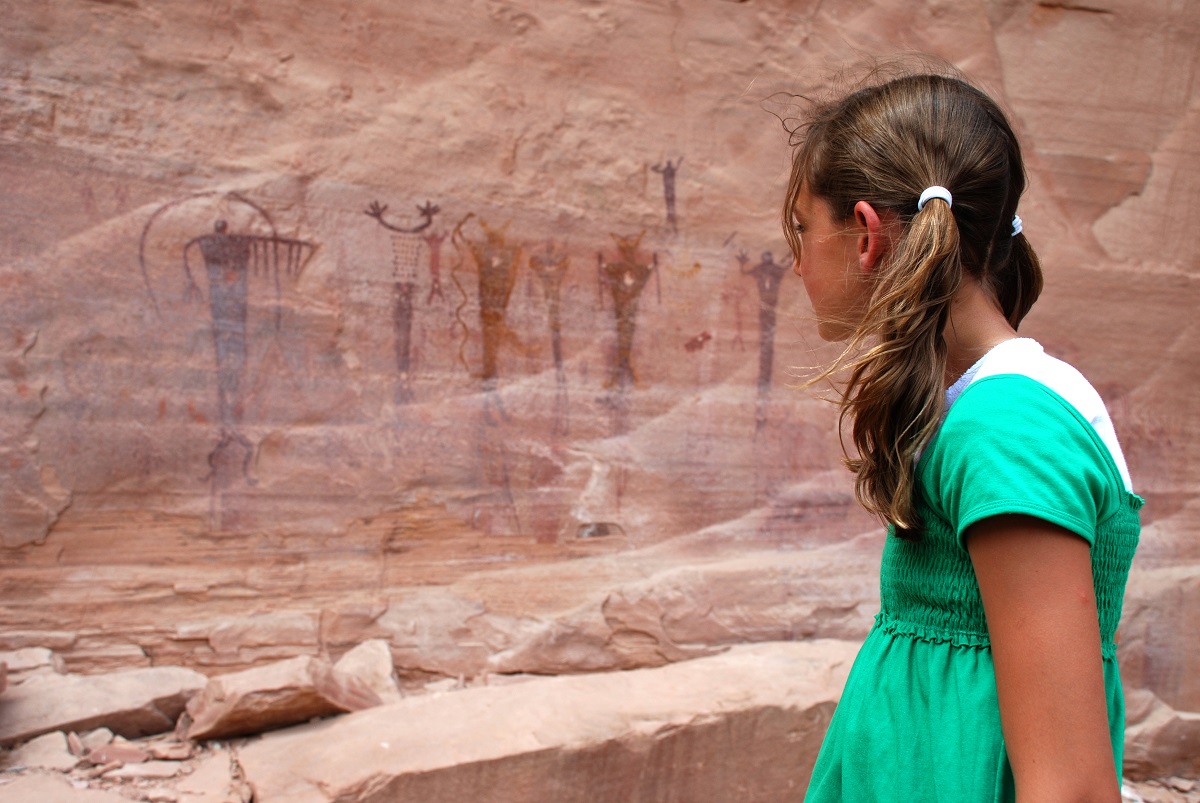 A young girl looks at rock art created by prehistoric humans