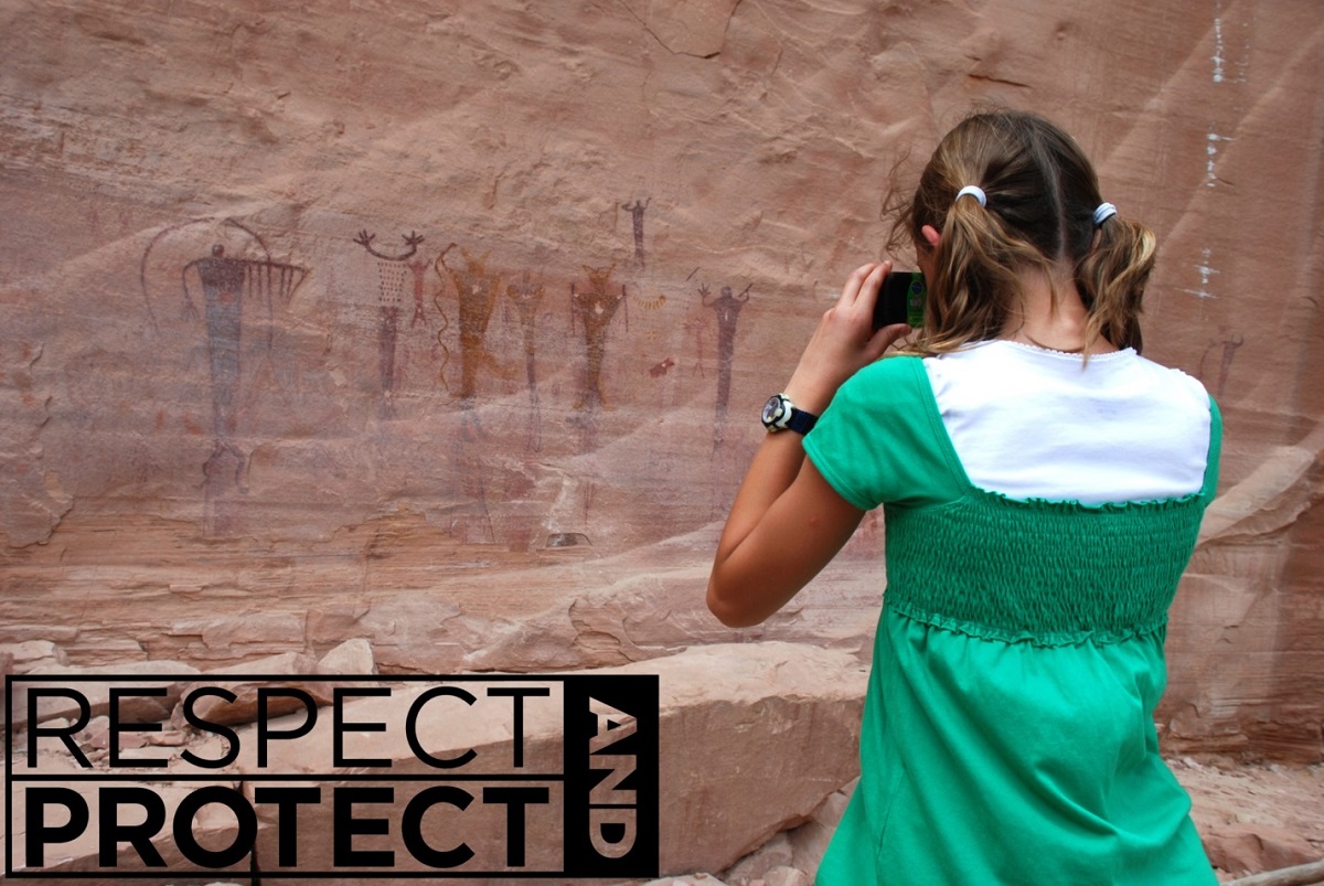 Woman photographing petroglyphs at Monarch Cave, Utah