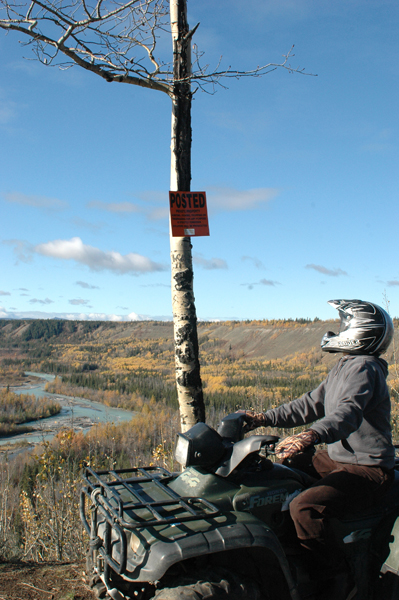 ATV rider looking at sign posted on tree