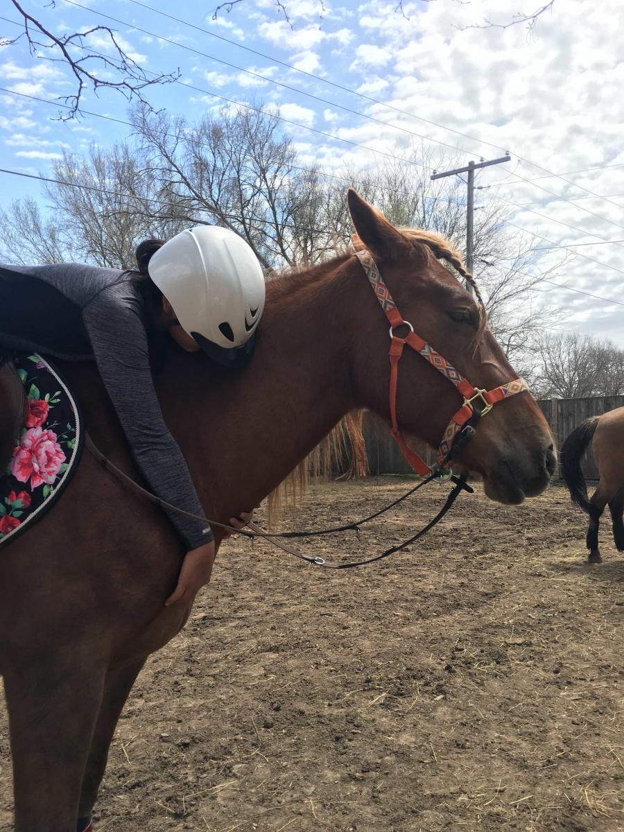 Woman riding horse, hugging its neck. 