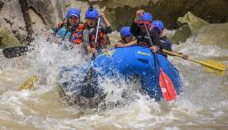 A group of people in a river raft on choppy waters.