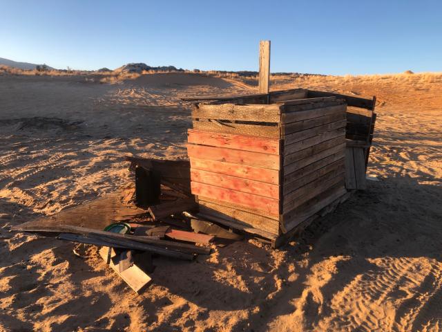 A old wooden chicken coop at a recreation site. Chicken wire and hold boards are shown.