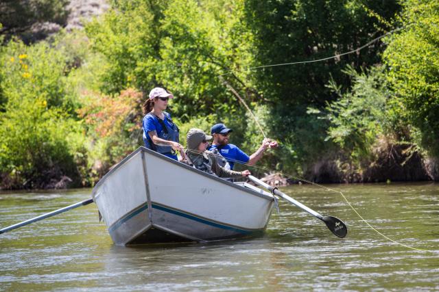 An outfitter guides two clients flyfishing from a drift boat on the Upper Colorado River.