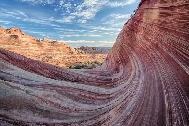 a rock feature with swirling red, orange and tan rock layers