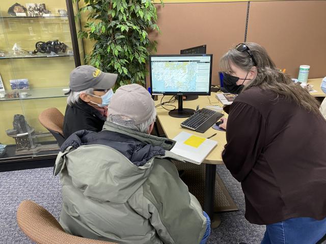 Two men and a woman looking at a computer screen.