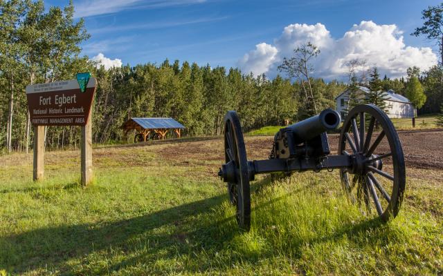 A replica cannon and sign next to a gravel road