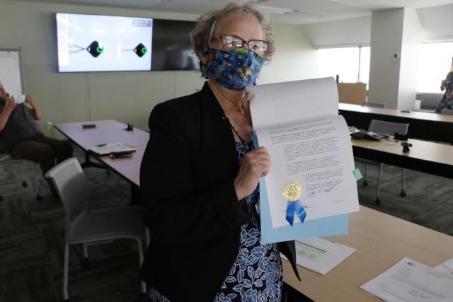 A woman holds up a final land patent. 