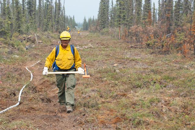 Firefighter walking with Pulaski in hand