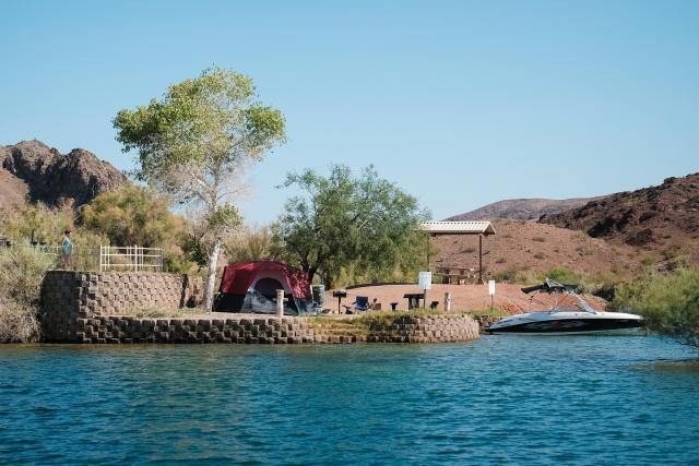 Campsite on a lakeshore with a boat tethered next to it.