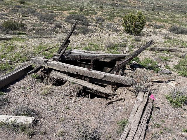 A 100-foot deep, open mine shaft with collapsing wooden collar.