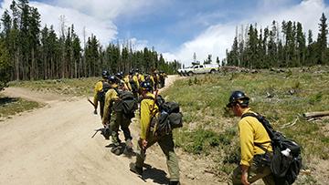 Firefighters in full gear walking up gravel road