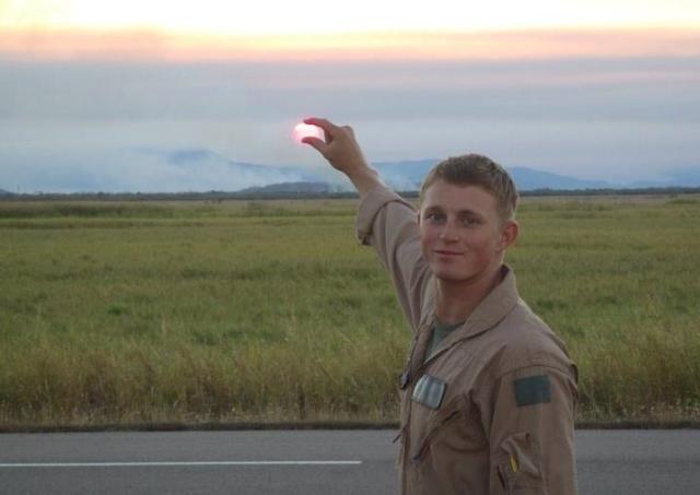 Man standing in desert pointing at setting sun