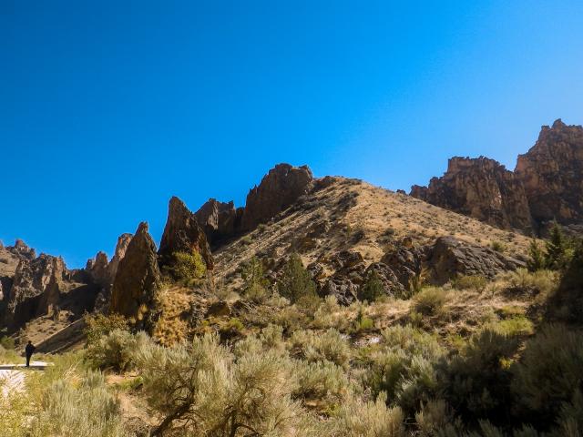 Standing on the dirt road, a person looks very small compared to the stone features in the gulch.