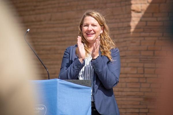 Melanie Barnes standing at the podium and clapping.