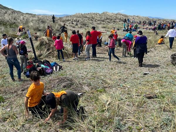 Students standing around the dunes, with two students kneeling in front