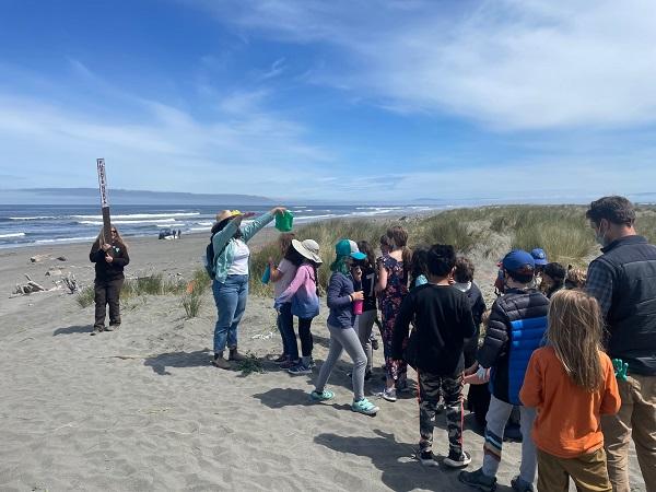 Students walking on the sand with a BLM staff member holding up a sign. 