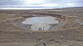 brown dry land surrounds water at a dam