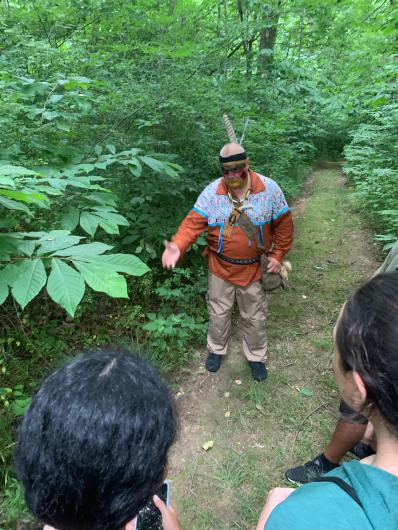 Indigenous teacher pointing to a plant with two NYCALC participants looking on