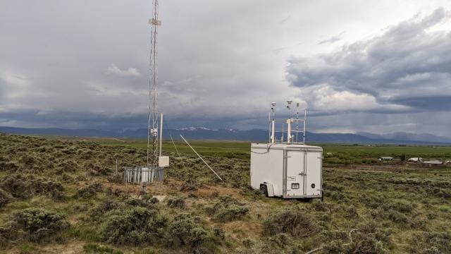 A photo of a small trailer beside a telephone pole.