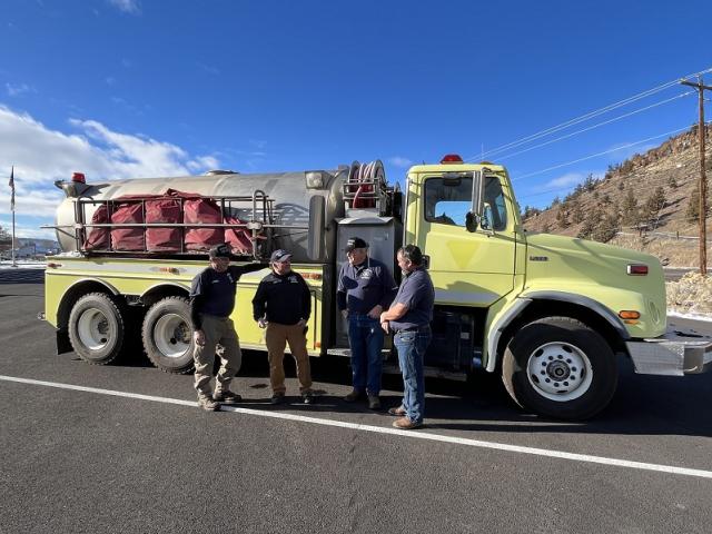 Wheeler County Fire and Rescue RFPA firefighters discuss fires from the past summer in front of the water tender