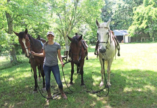 Woman stands with three horses.