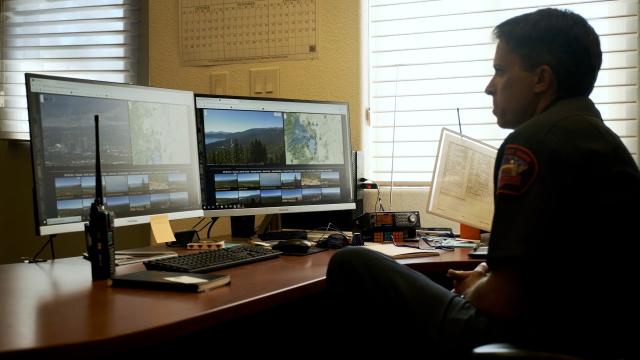 Employee monitoring remote fire camera at an office computer.