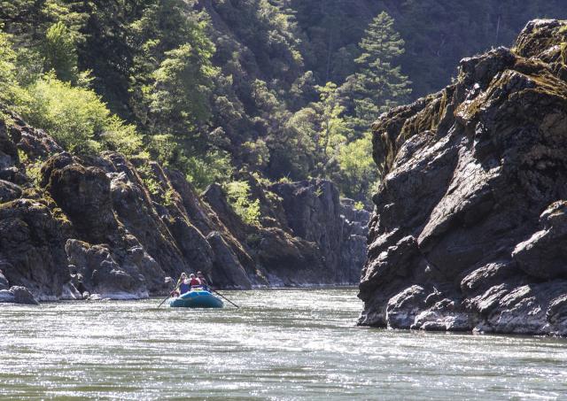 boaters float downstream in a river between high jutting rocks