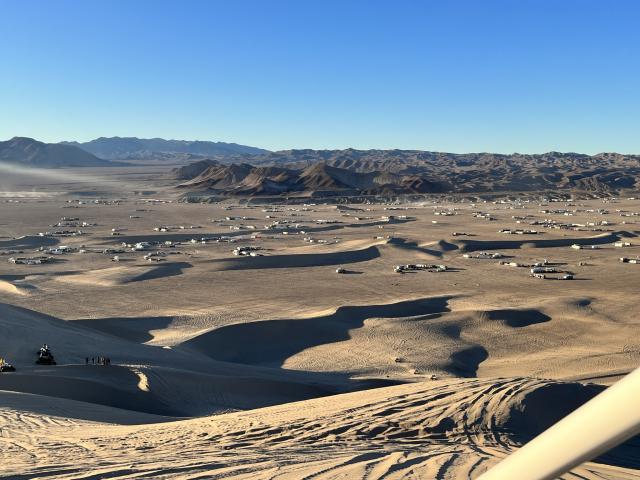 A dune sea and RVs in a staging area.