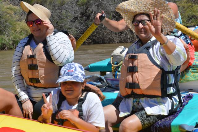 Two adults and one youth on a yellow raft on a river.