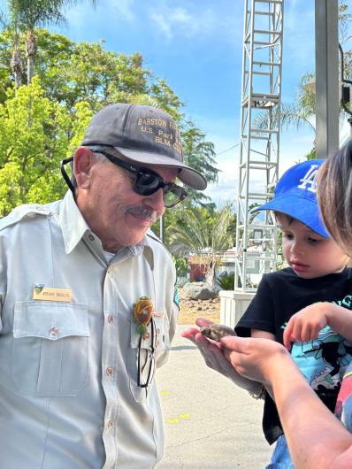 Art Basulto shows a tortoise to a group of kids at a fair booth.