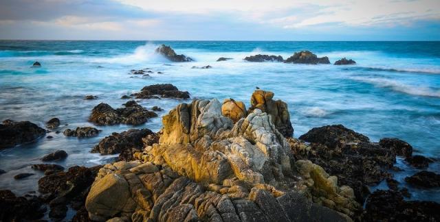 Water  sprays over rocks on the ocean shore