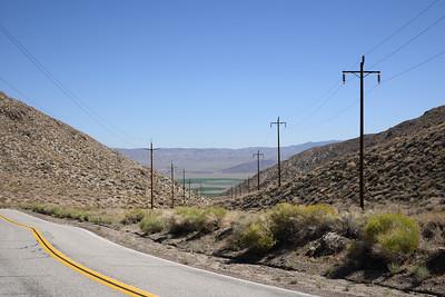 Transmission lines stretch across a brush covered hills.