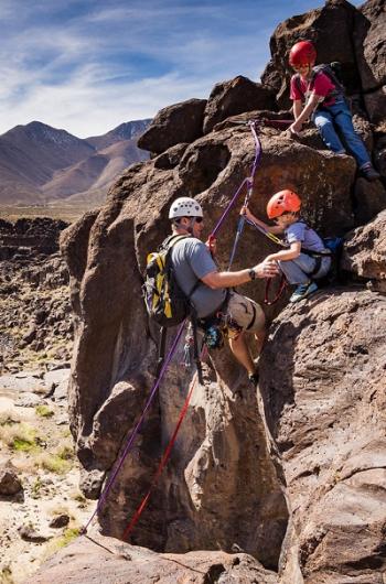 A dad and his sons repel down a rock wall.