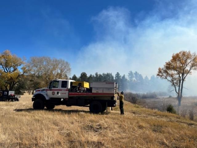 A firetruck engine on a grassy landscape. 