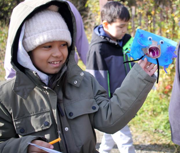 A student shows off the blue critter they created with craft items. 