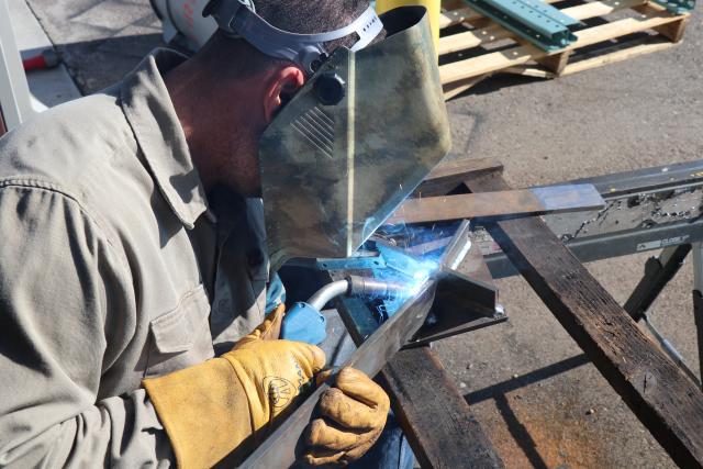 a person welds a cross-shaped steel target.