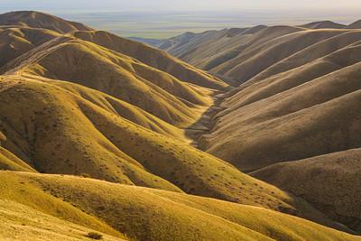 Sun rises over golden hills.