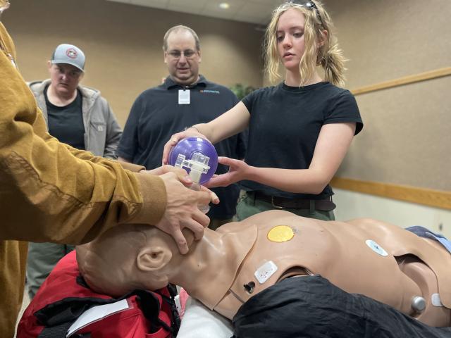 Woman in black shirt uses medical equipment on a medical mannequin..