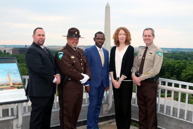 Five people standing on top of a building with the National Monument in the background. 