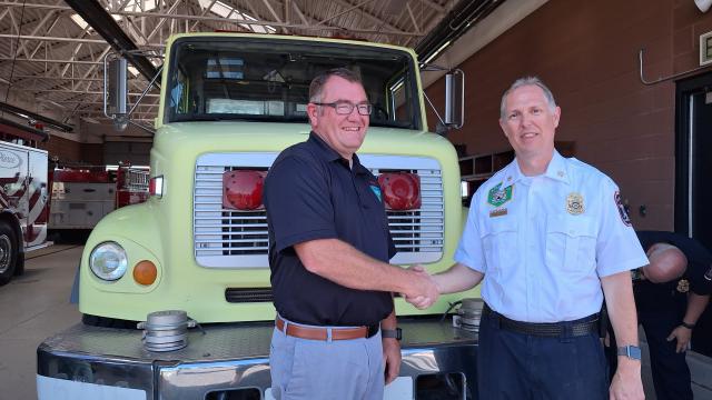 WDD manager Mike Gates shakes hands with NTFD Chief Kevin Nunn in from of the water tender