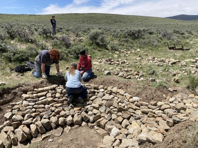 a group of workers piling rocks in a stream channel