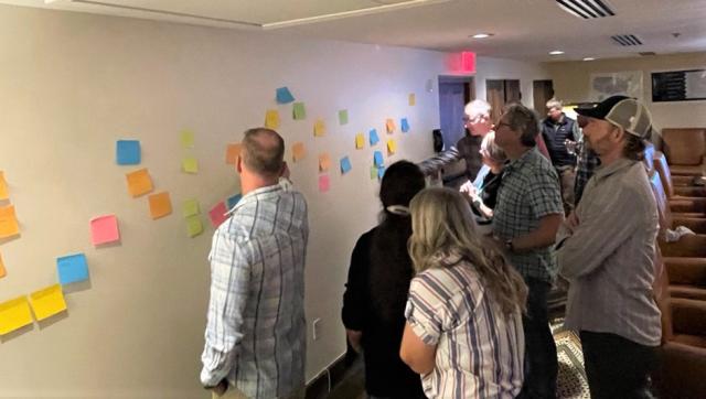 Caucasian adults place colorful post its on a white wall