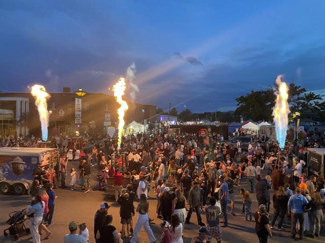 Fire explodes from hot air balloon baskets at night. The crowd of Dinah Days looks on. 