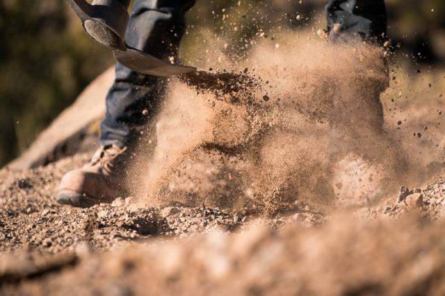 Dirt flies up from the ground onto laced boots and denim jeans