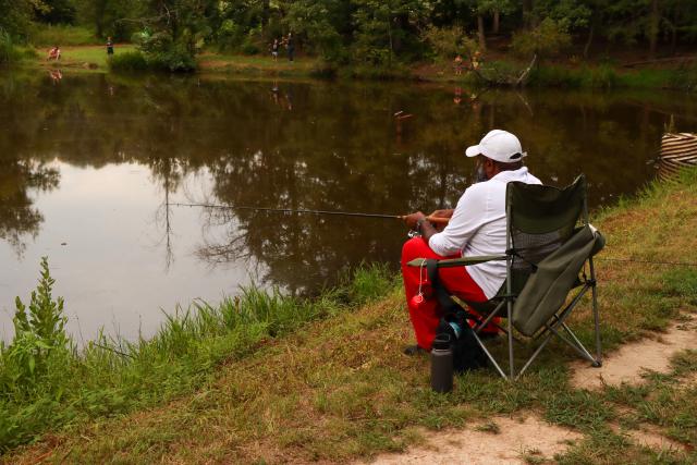 A veteran fishes from a folding chair at Meadowood SRMA’s Hidden Pond 